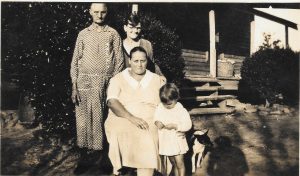 Photo of four women sitting in their farmhouse yard in 1933