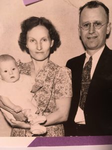 A married couple poses with their infant.